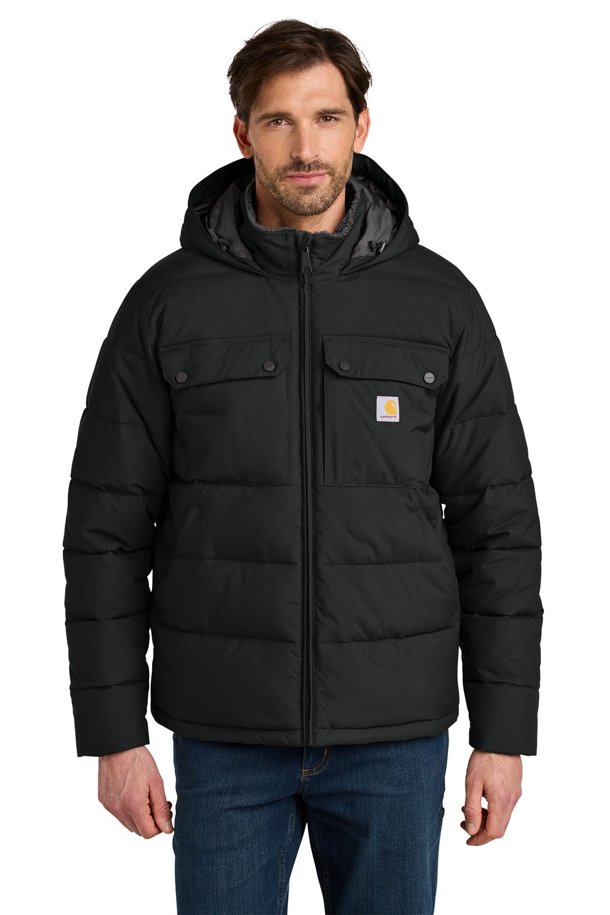Man wearing a brown, hooded Carhartt puffer jacket, in front of a neutral backdrop.