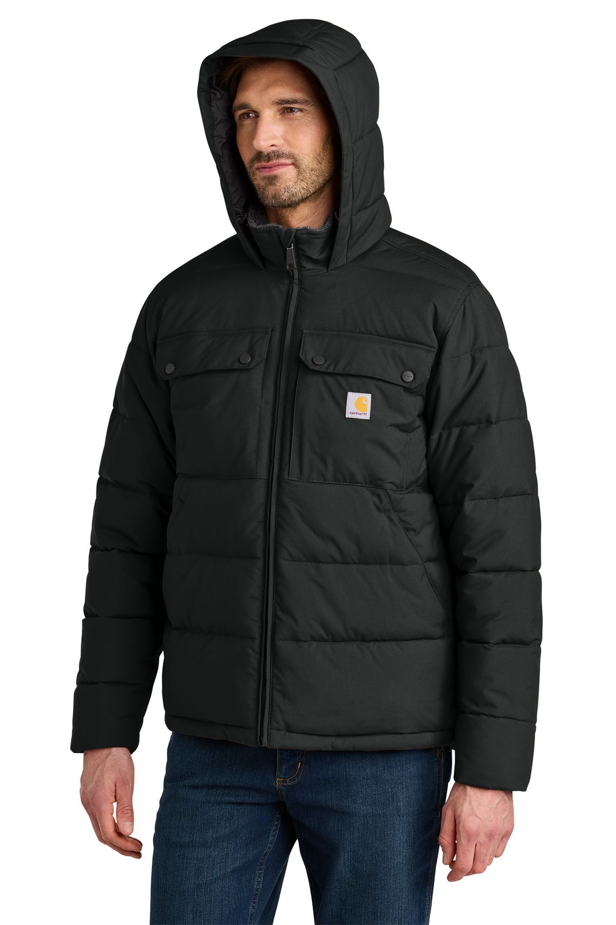 Man wearing a black Carhartt hooded puffer jacket and jeans.