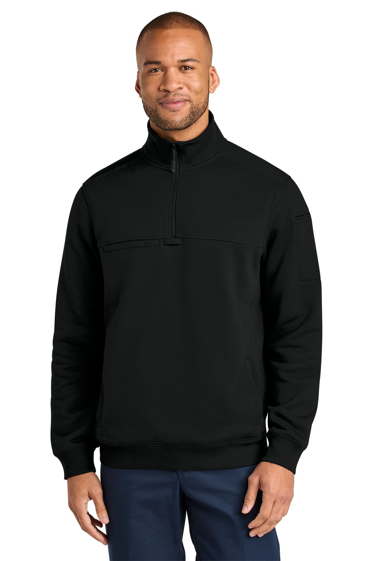 Man in black half-zip sweatshirt and blue pants, smiling. Front view.