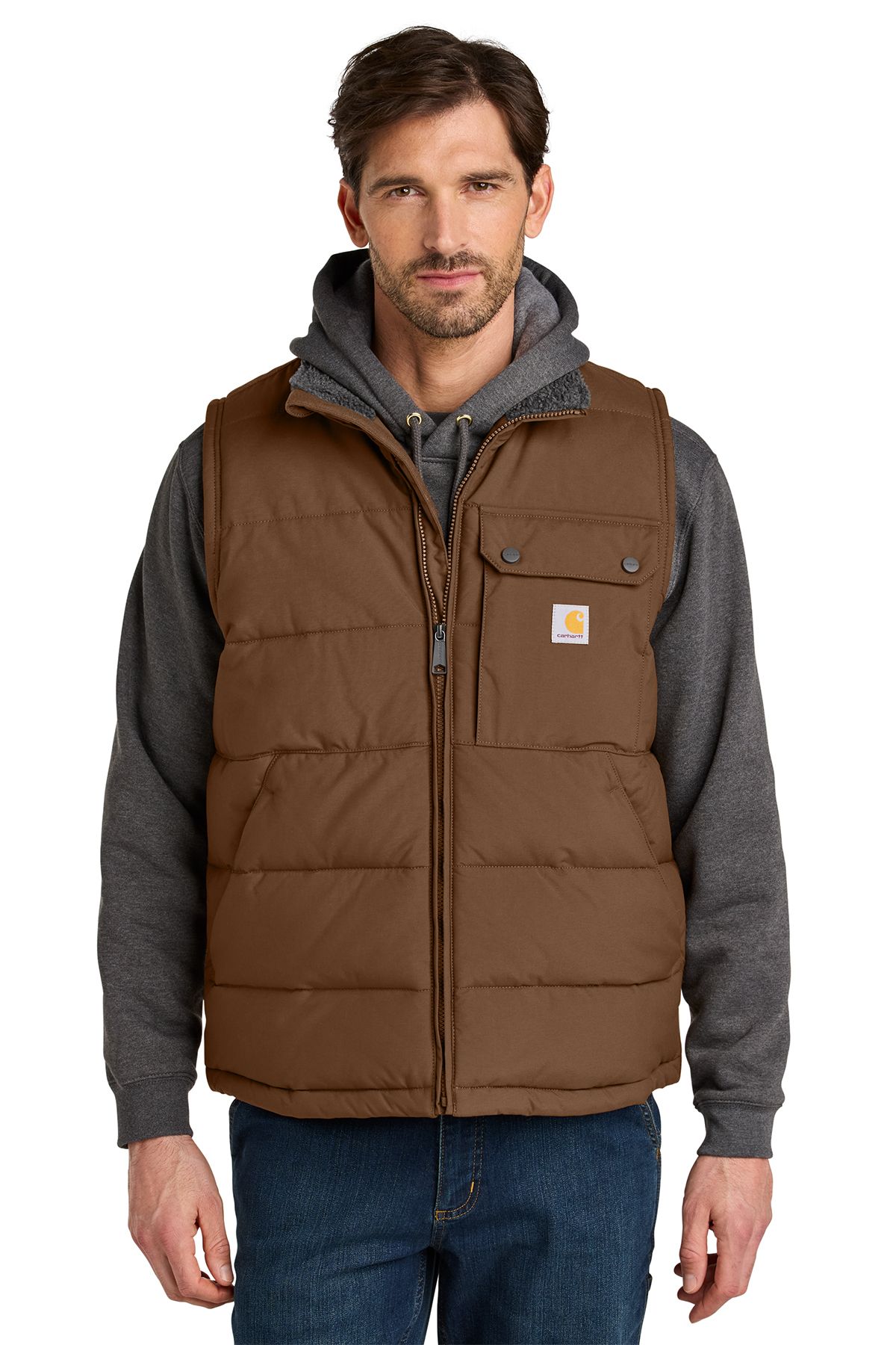 Man wearing a black puffer vest over a gray hooded sweatshirt and blue jeans.