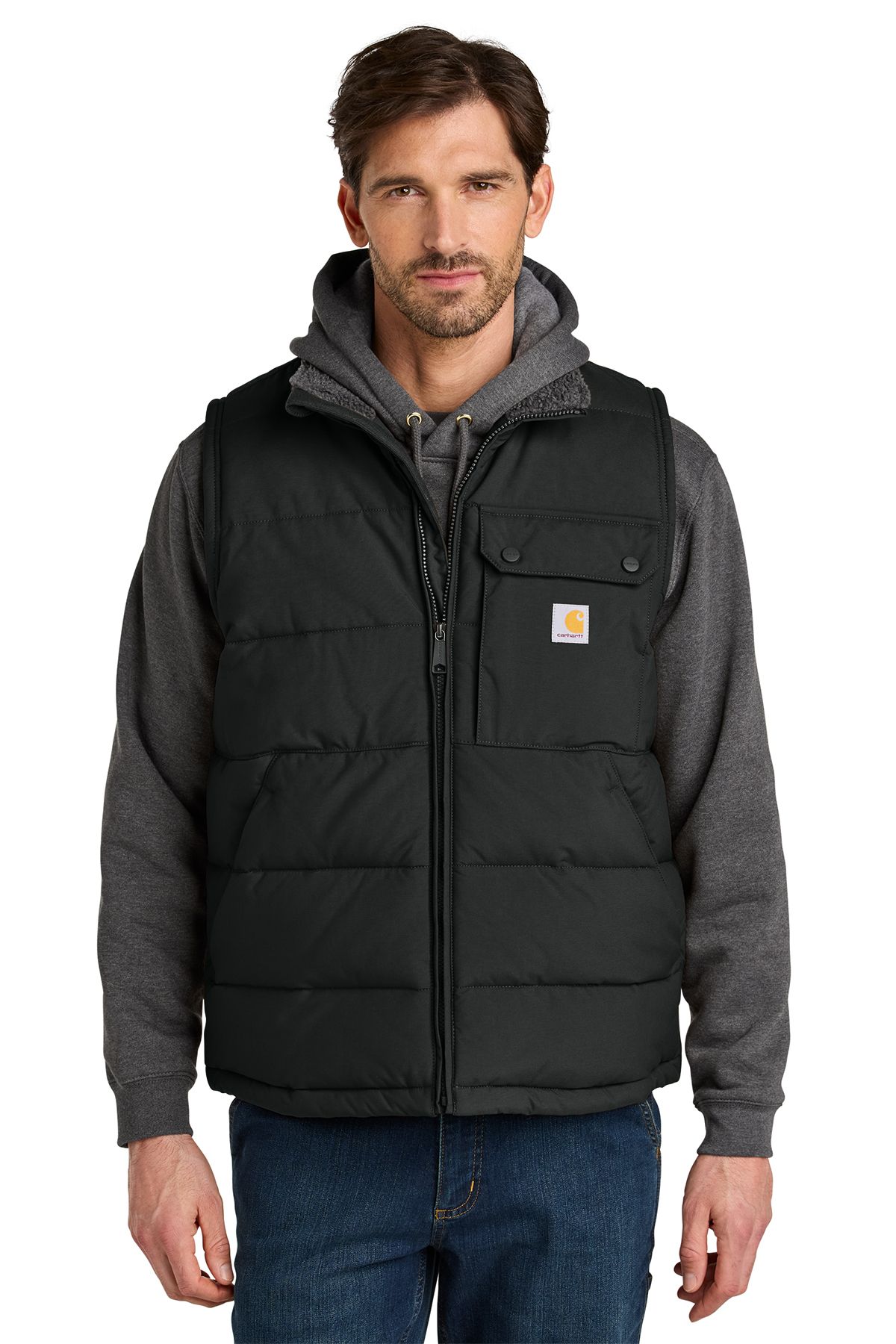 Man wearing a black puffer vest over a gray hooded sweatshirt and blue jeans.