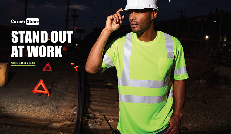 Wholesale Workwear Man wearing neon work shirt and hard hat, standing near railroad tracks,