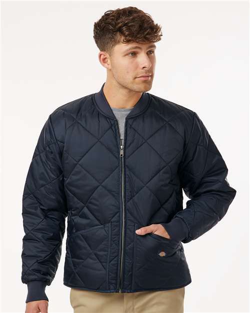 Man in a navy blue quilted jacket with a zipped front, hand in pocket.