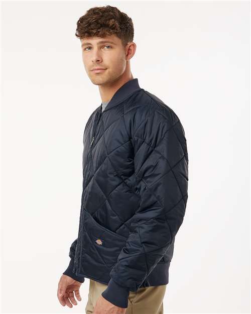Man in a navy blue quilted jacket with a zipped front, hand in pocket.