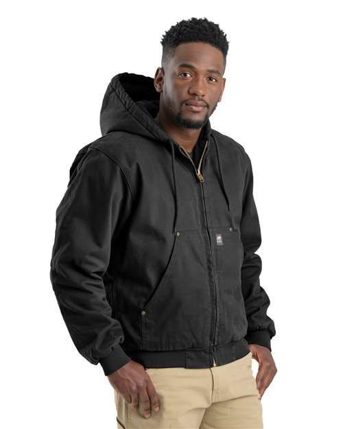 Man in black hooded jacket, tan pants, looking forward.