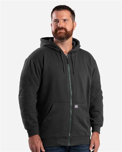 Man in a green zip-up hoodie with a beard, in a studio setting.