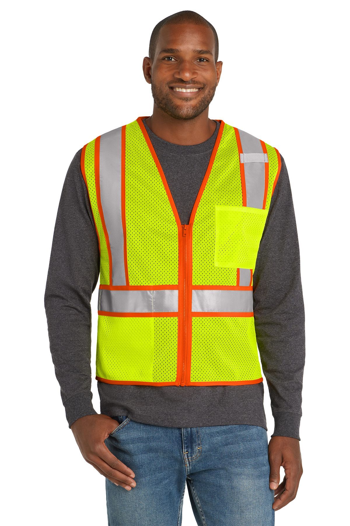 Man wearing a neon yellow safety vest with orange trim, smiling, standing indoors.