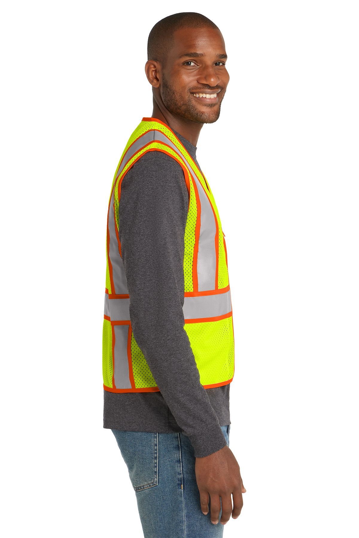 Man wearing a neon yellow safety vest with orange trim, smiling, standing indoors.