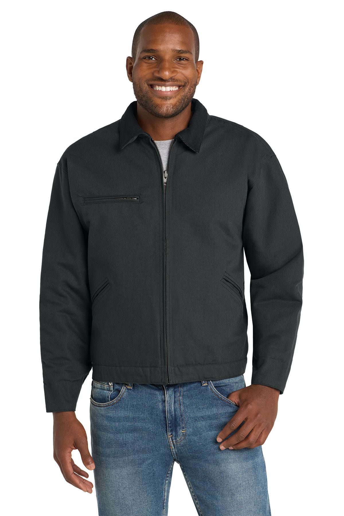 Man wearing a brown work jacket, blue jeans, and a grey shirt; smiles.