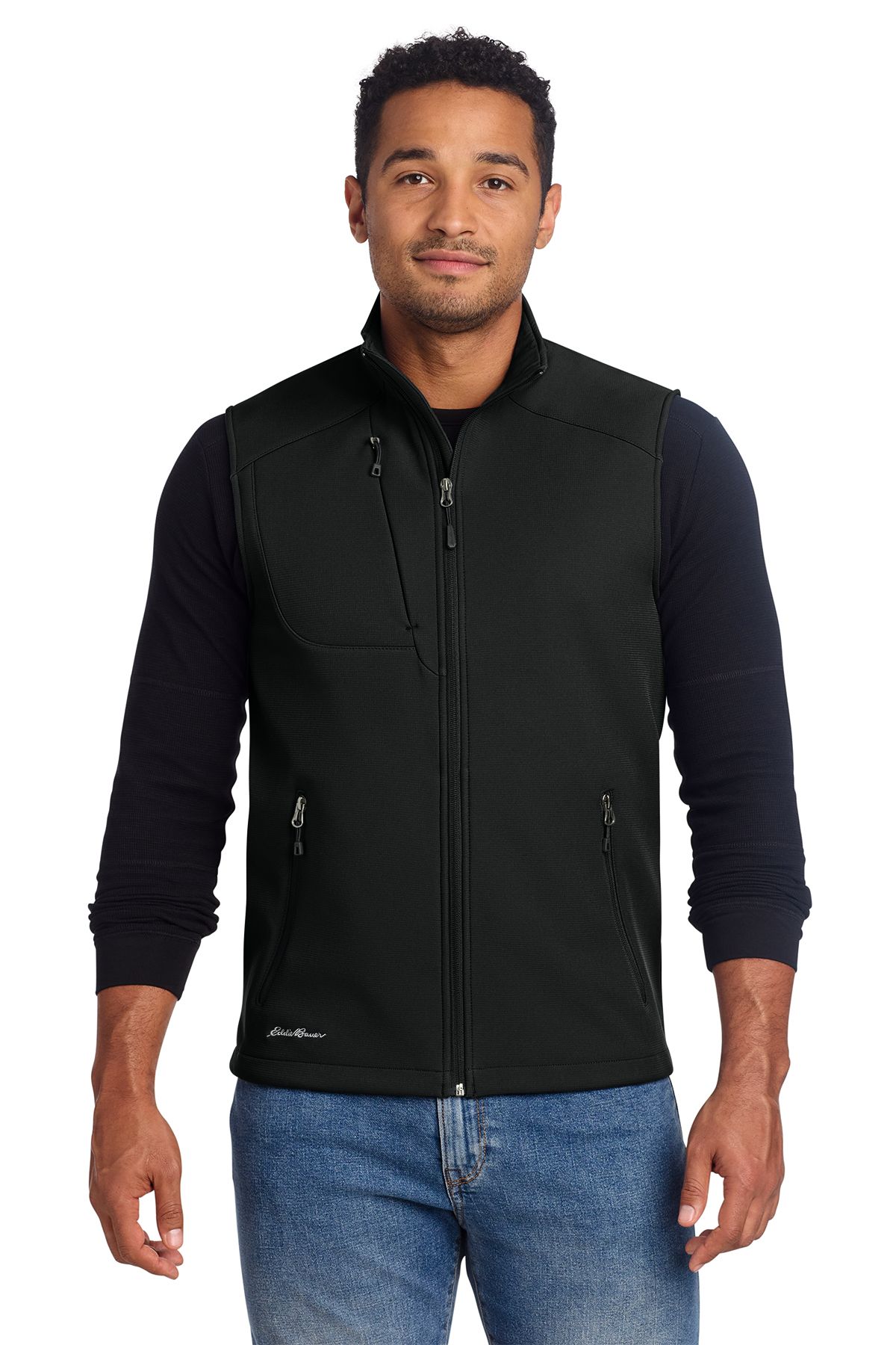 Man wearing a black vest and long-sleeved shirt over blue jeans.