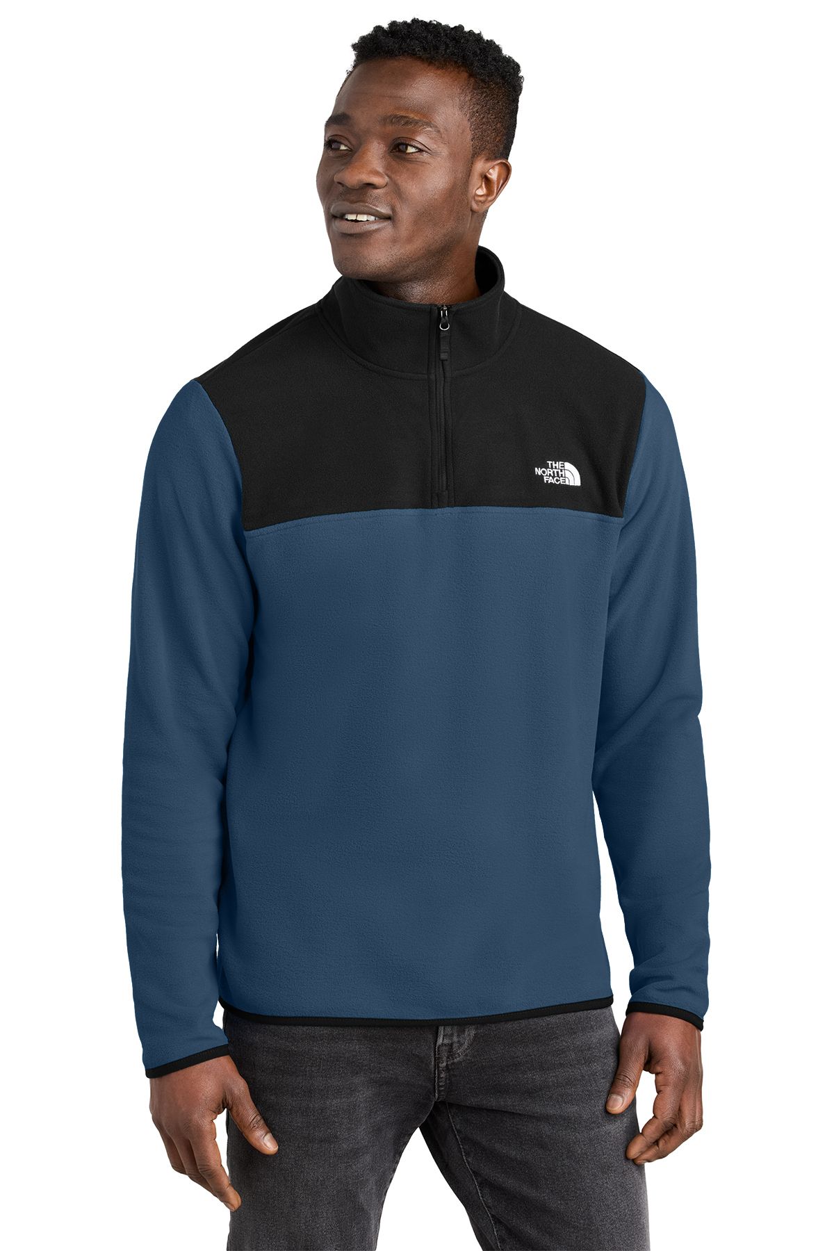 Man wearing a blue and black North Face fleece jacket, standing in front of a white background.