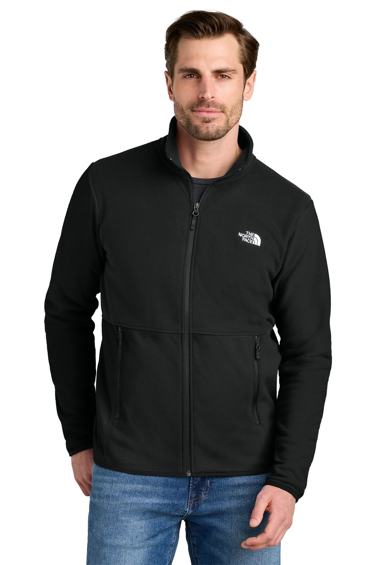 Man in black fleece jacket, hands in pockets, wearing jeans. White North Face logo on chest.