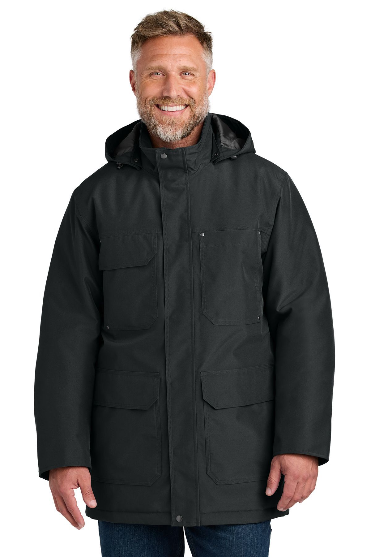Man in a black winter coat with a hood and multiple pockets, smiling.
