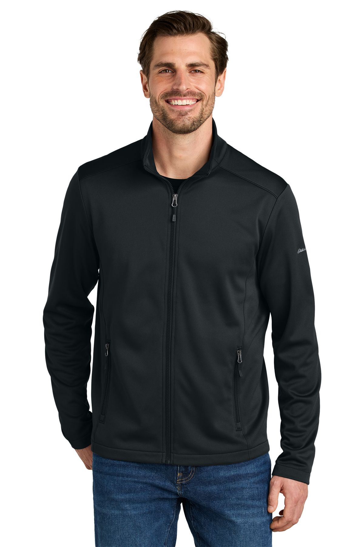 Man wearing a black zip-up jacket over jeans, standing in front of a white background.