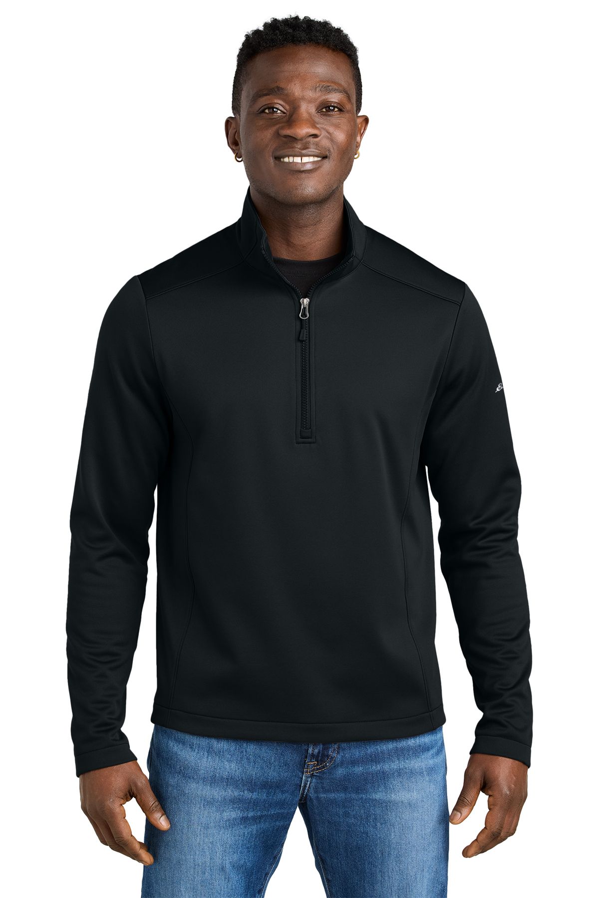 Man in black quarter-zip sweatshirt and jeans, smiling, standing against a white background.