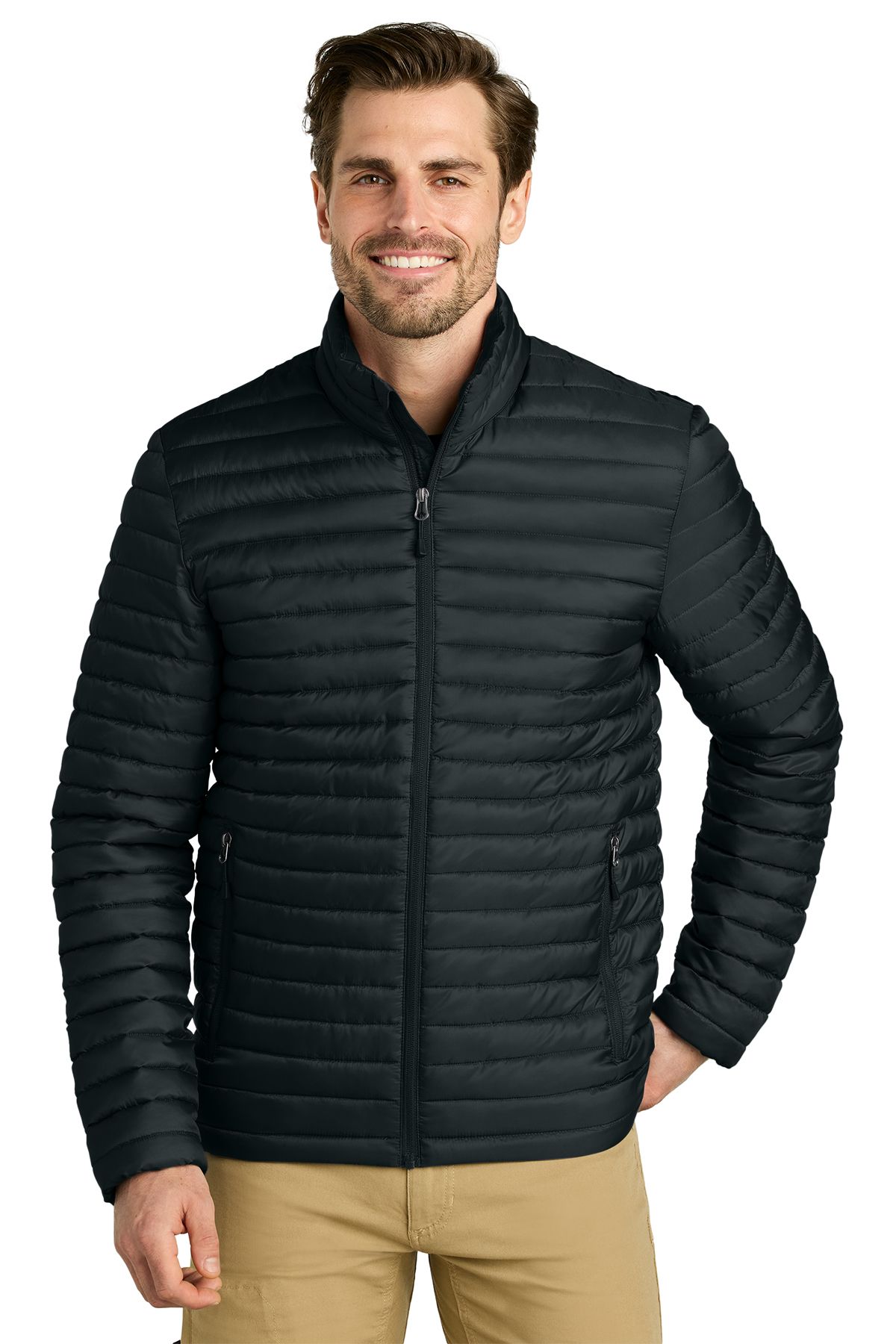 Man in a black quilted jacket smiling, wearing khaki pants.