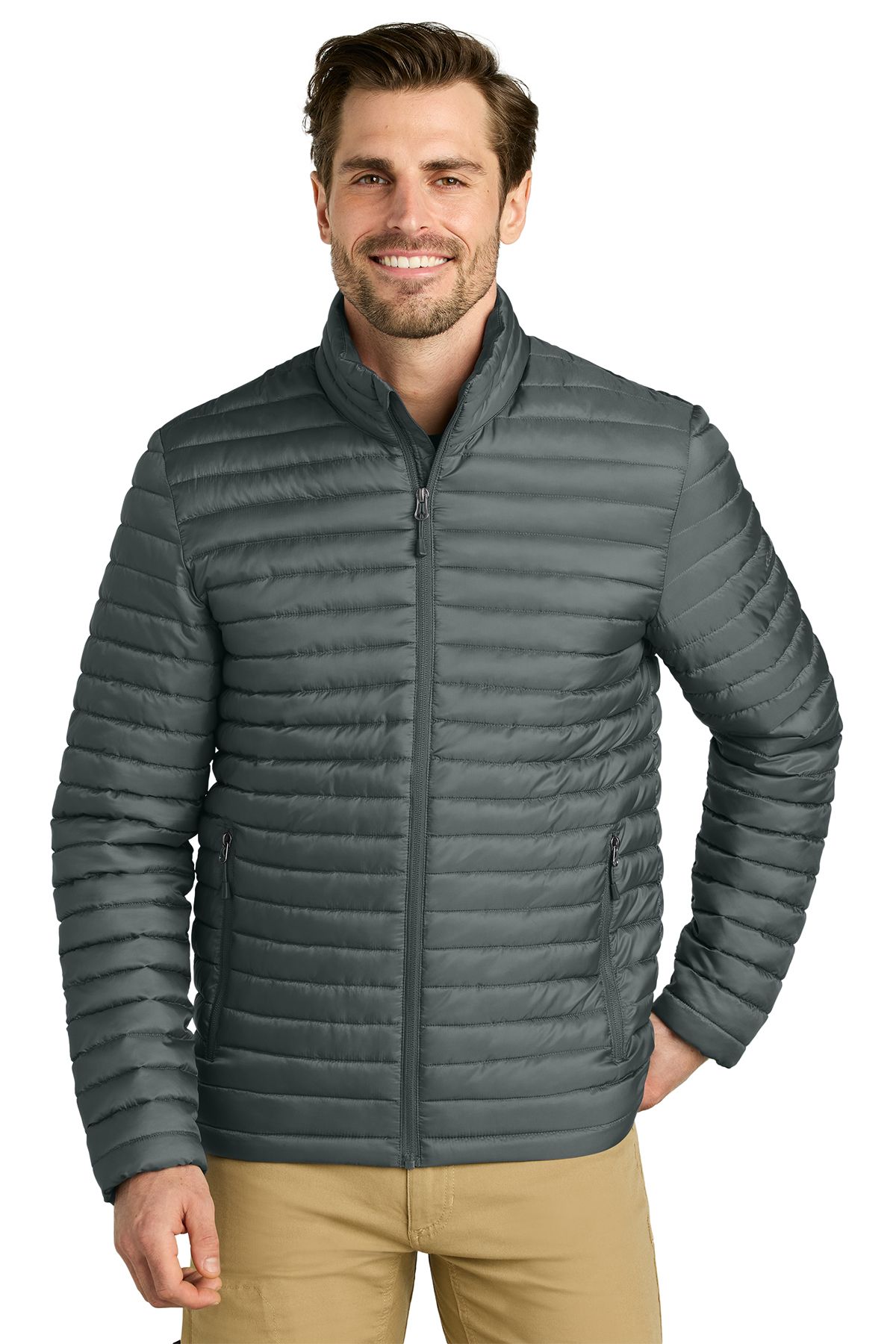 Man wearing a dark green, quilted jacket with beige pants, smiling.