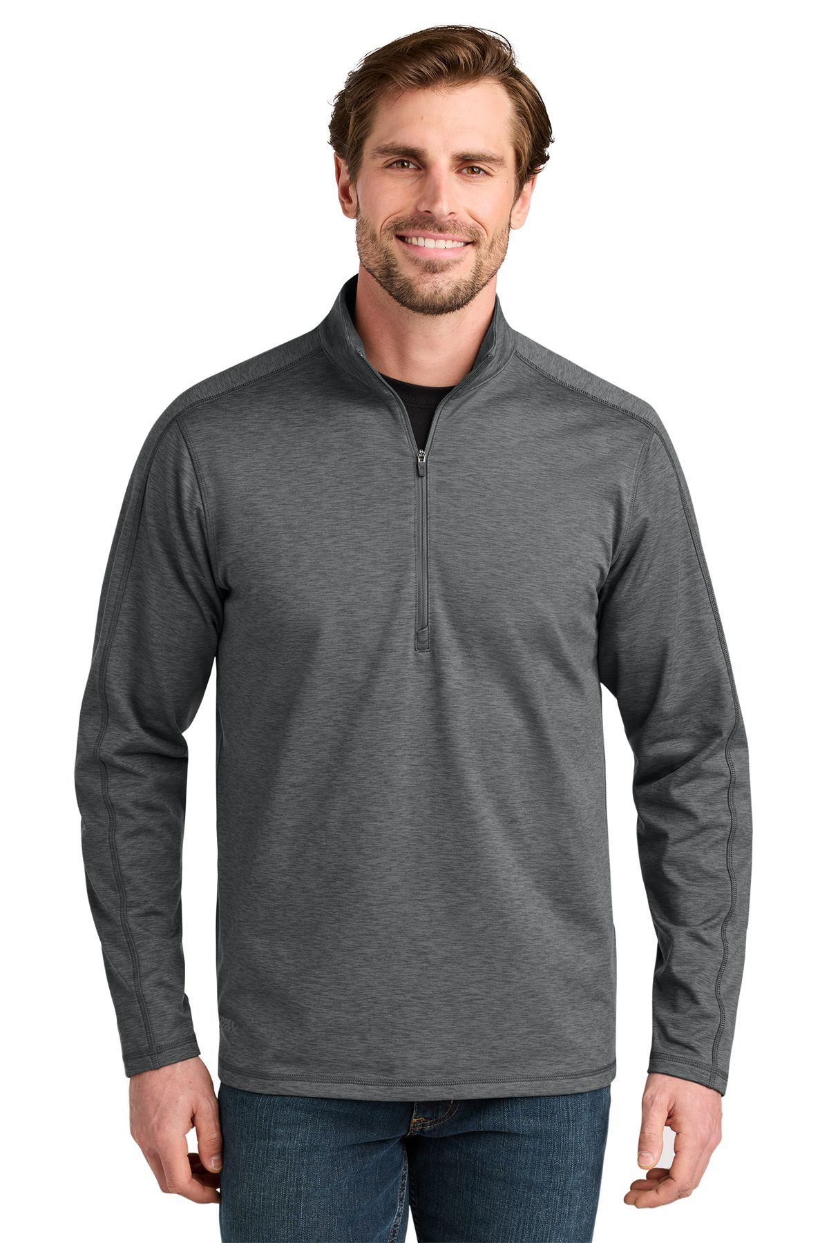 Man in a blue quarter-zip sweatshirt smiles, standing outdoors.