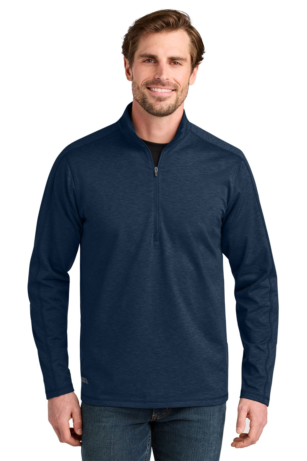 Man in a blue quarter-zip sweatshirt smiles, standing outdoors.
