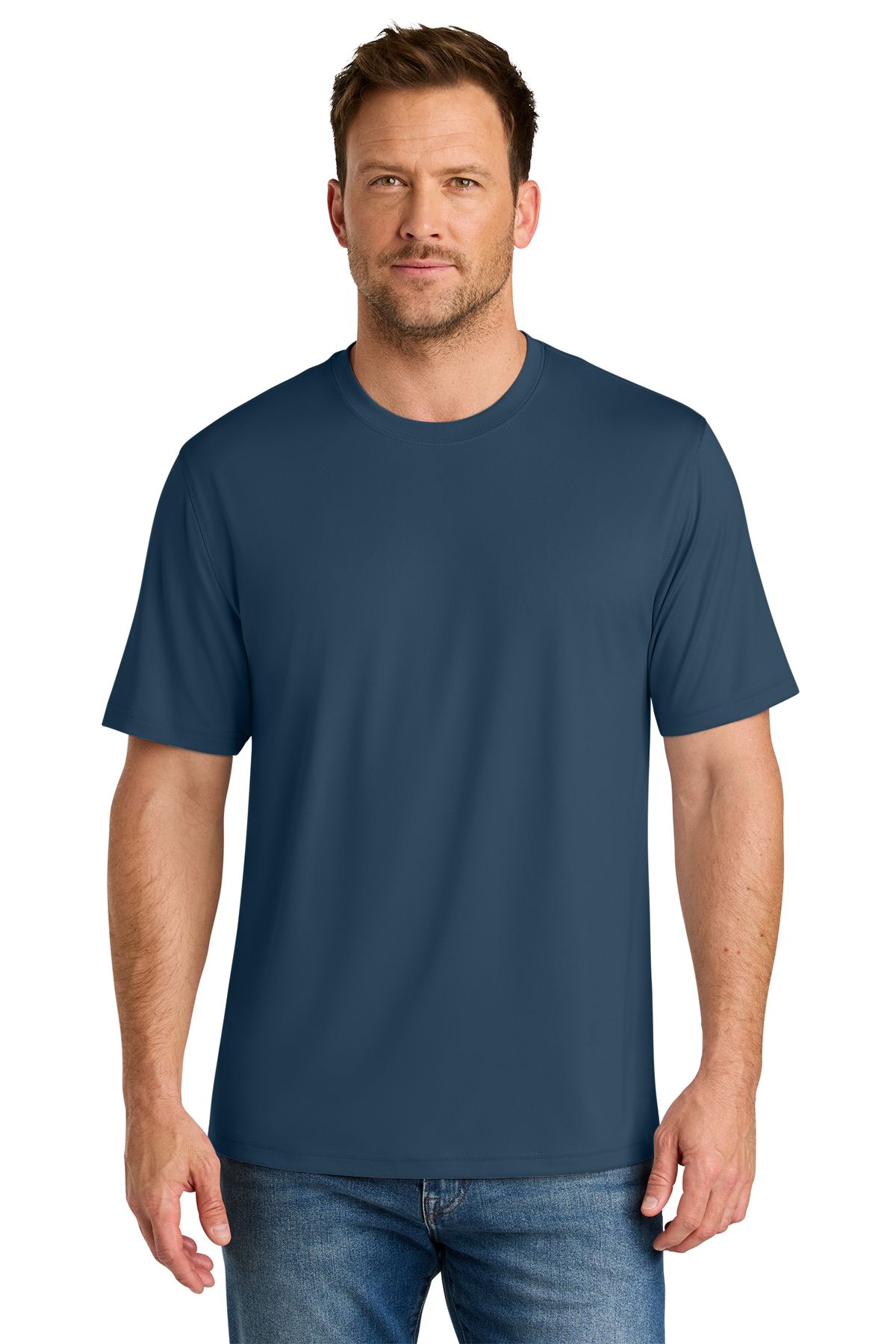 Man in a blue crew-neck t-shirt and blue jeans, standing indoors, looking at the viewer.
