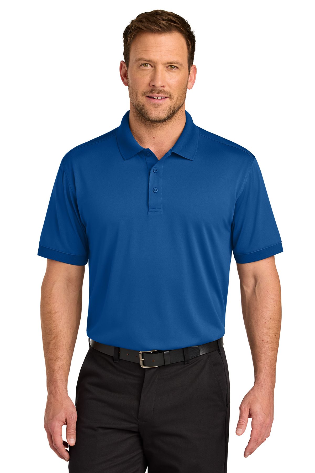 Man wearing a blue polo shirt and black pants, smiling, standing against a white background.