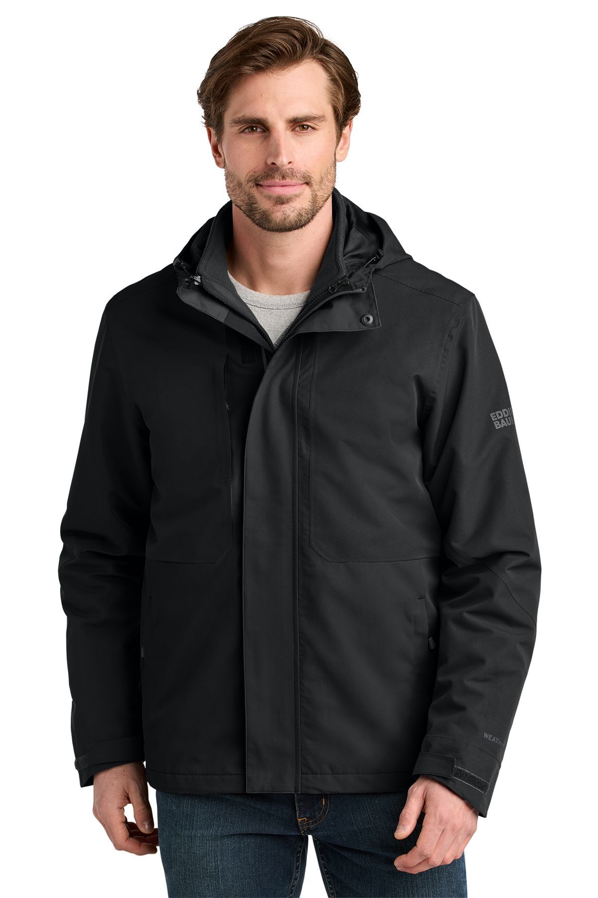 Man wearing a black jacket with a hood, standing against a white background.