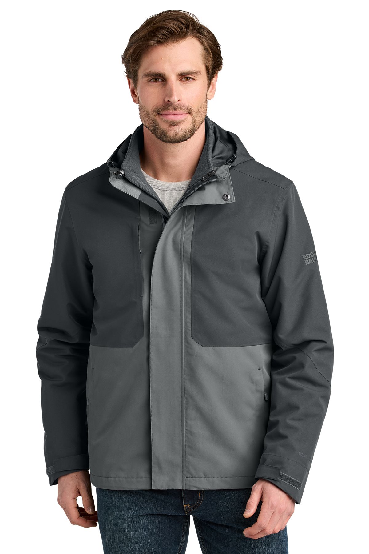 Man in dark gray and light gray winter jacket with hood, in a studio setting.