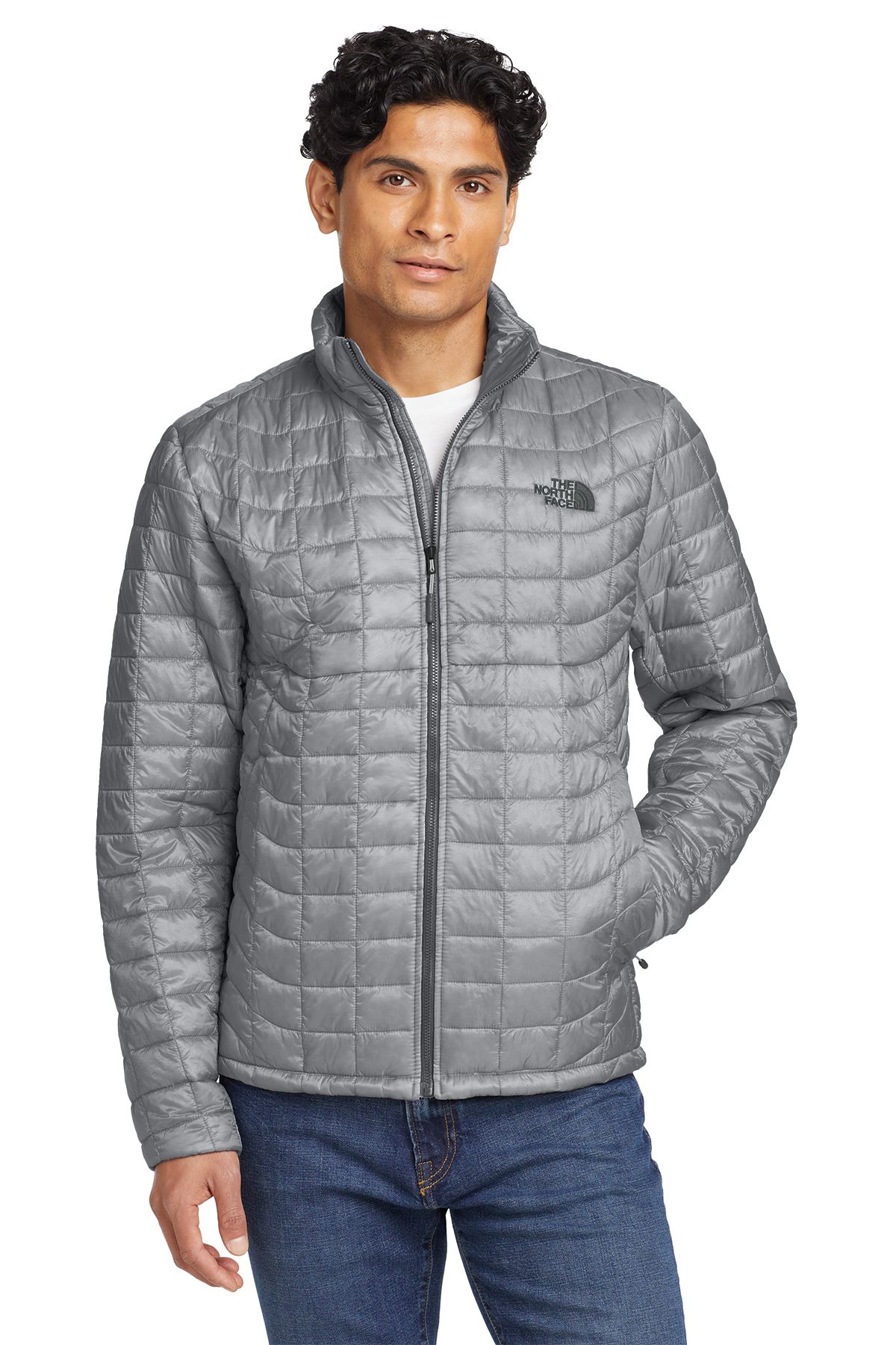 Man wearing a gray quilted jacket over a white shirt, standing in front of a neutral background.