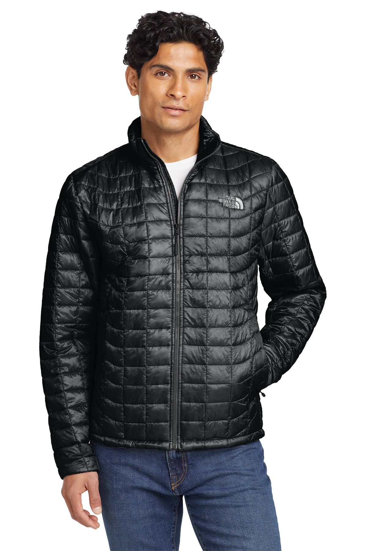 Man wearing a gray quilted jacket over a white shirt, standing in front of a neutral background.
