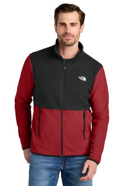 Man in a black and red North Face fleece jacket, standing in front of a white background.
