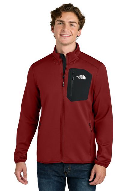 Man wearing a maroon North Face jacket with black chest pocket, smiling.