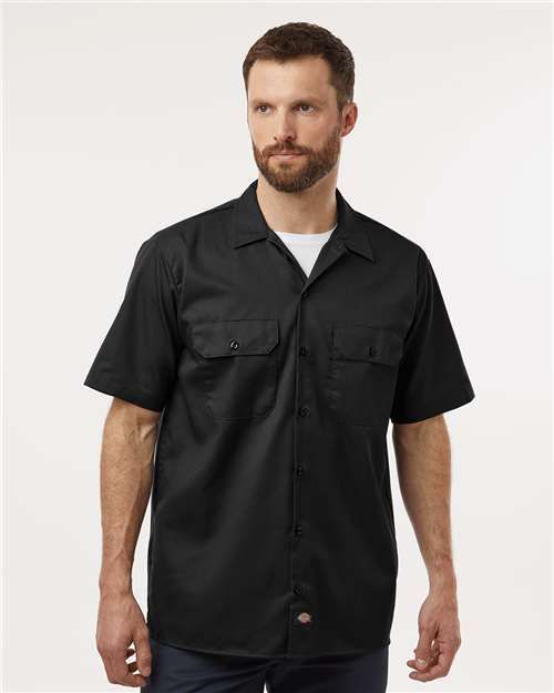 Man wearing a black short-sleeved work shirt with chest pockets.