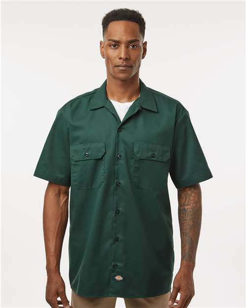 Man wearing a light blue short-sleeved button-up shirt with two pockets.