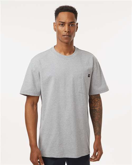 Man wearing a tan pocket t-shirt, standing and looking forward.