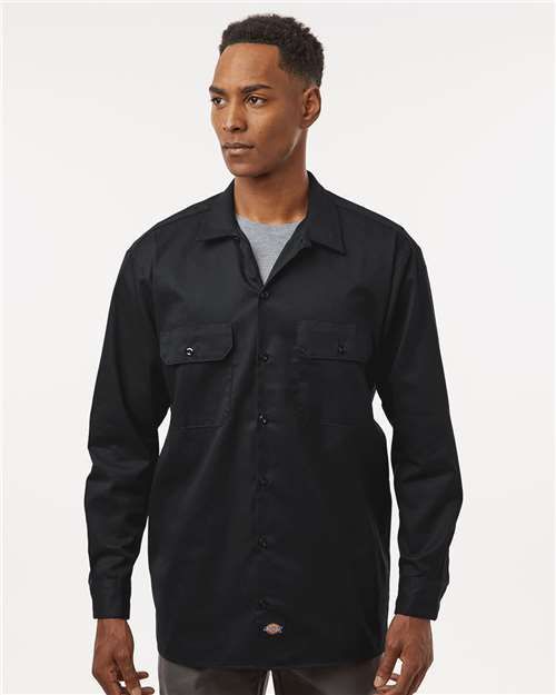 Man wearing a black button-up shirt over a grey t-shirt, looking slightly to the side.