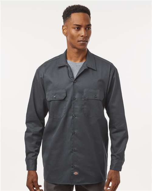 Man wearing a black button-up shirt over a grey t-shirt, looking slightly to the side.