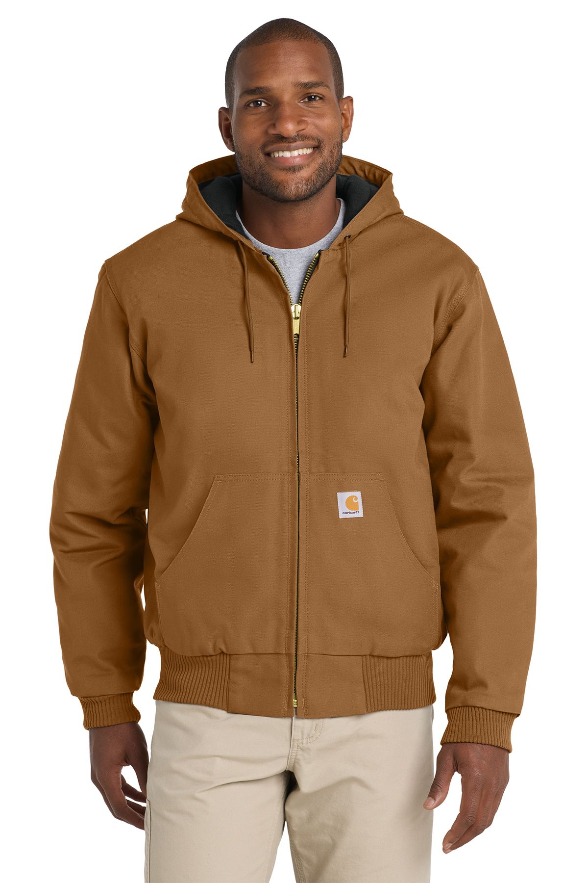 Man in gray hooded Carhartt jacket, khaki pants, smiling, outdoors.