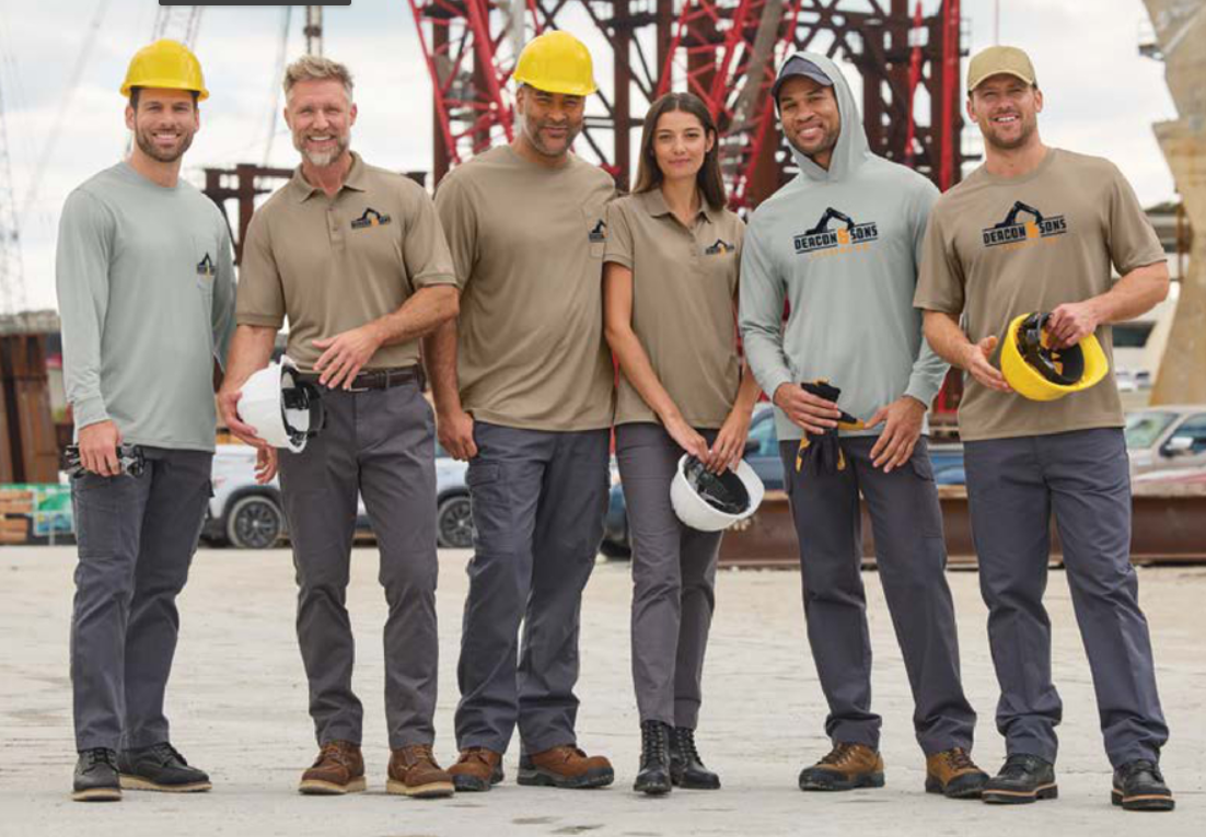 Construction workers in workwear and safety helmets, posing at a construction site.