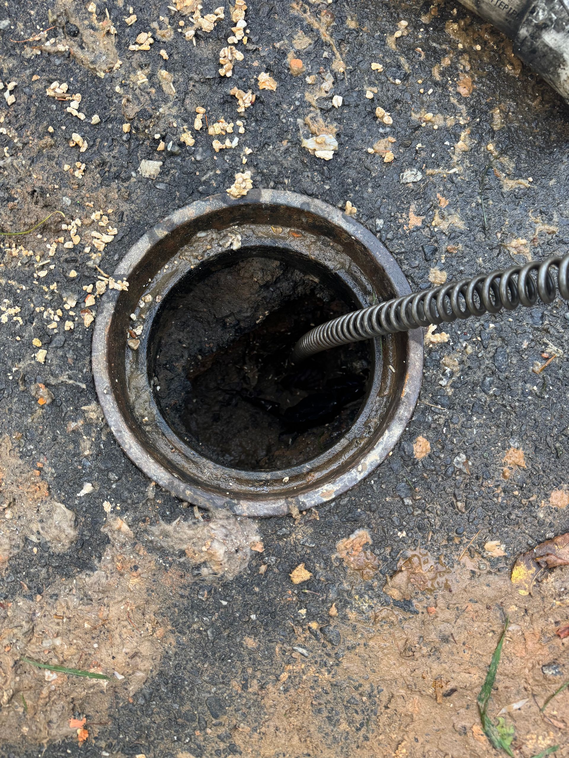 A drain machine cable going down a clean out to clear an obstruction in a drain line.