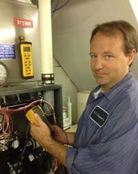 Hands using a screwdriver to work inside an open metal electrical cabinet, with wires visible.