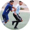 Two soccer players in blue and white jerseys running during practice on a field