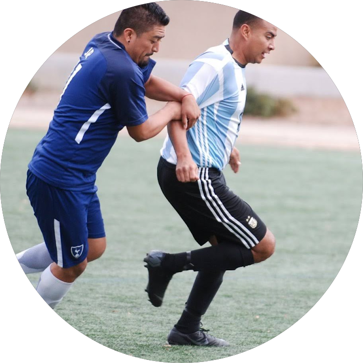 Two soccer players in blue and white jerseys running during practice on a field