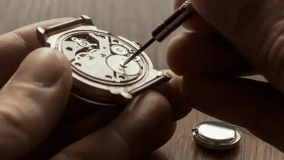 A pocket watch is being repaired on a table with tools.
