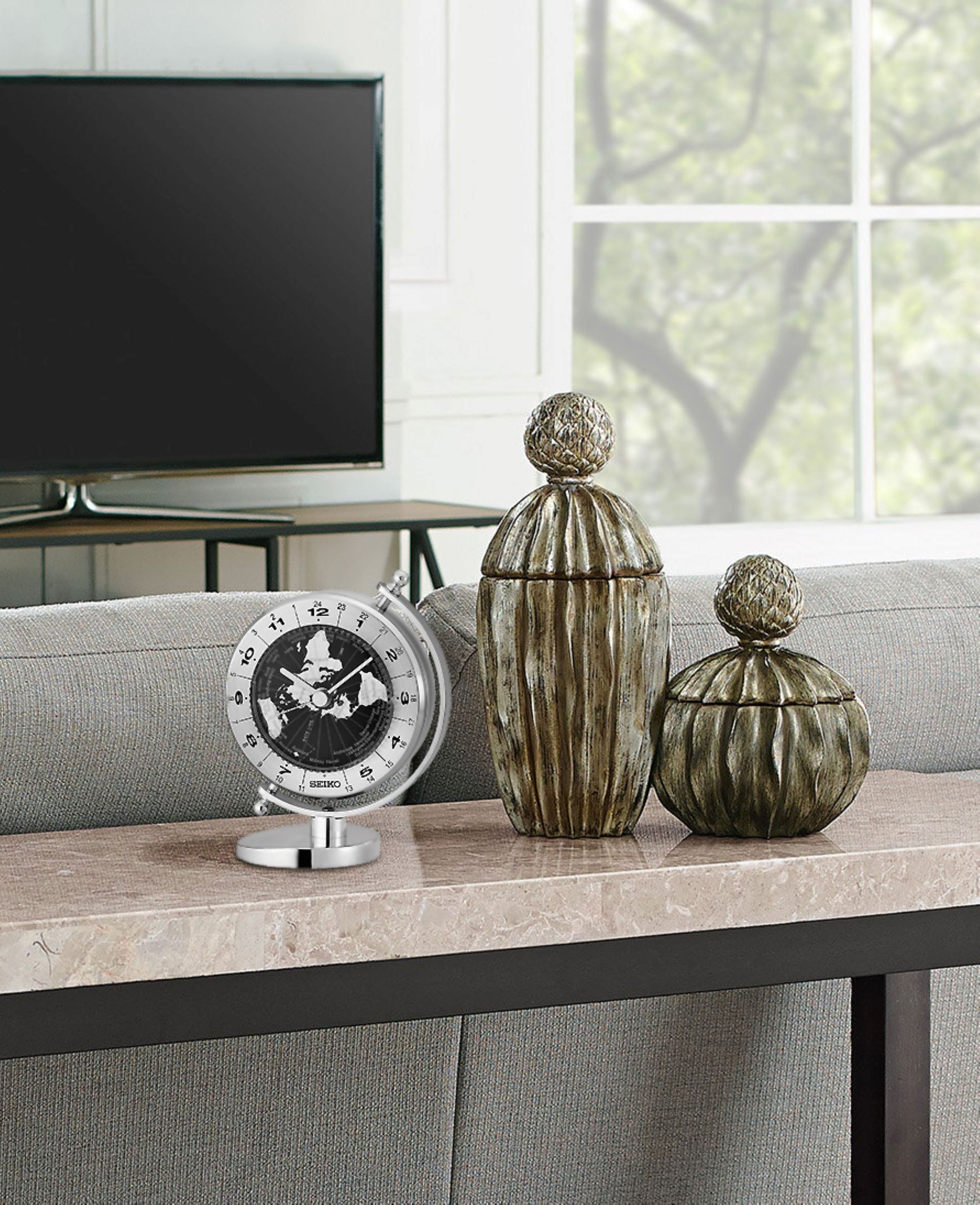 A clock and two vases are on a table in a living room.