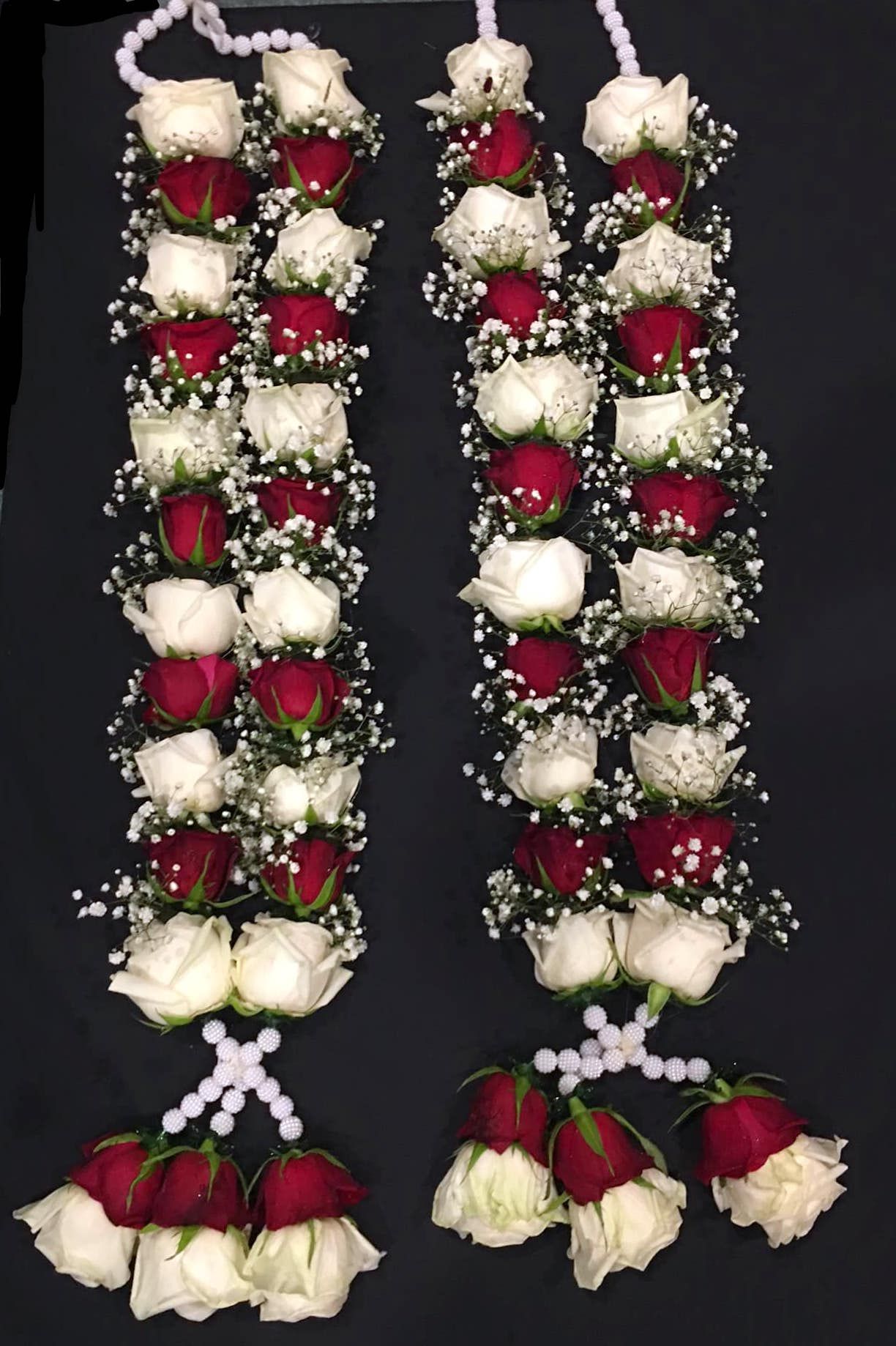 Two hanging floral garlands of red roses and white flowers, with rose clusters at the bottom