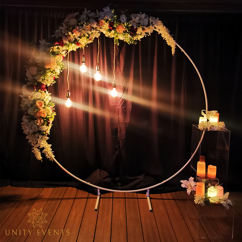 Floral-decorated circular backdrop with warm lights and candles on a wooden floor