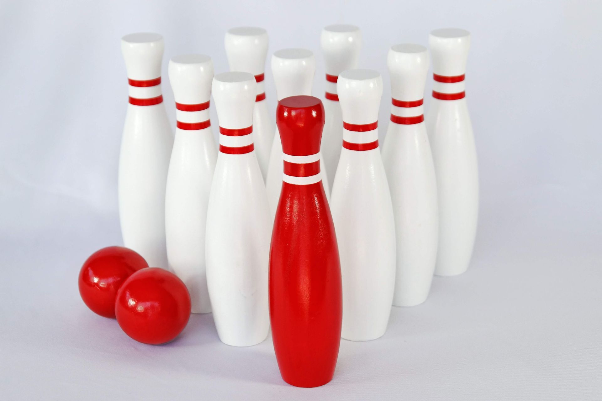 Red and white bowling pins and two red bowling balls on a white background