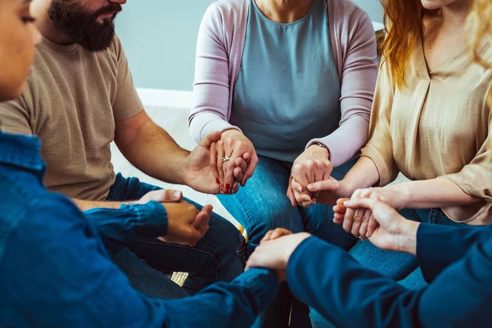 A group of people are sitting in a circle holding hands