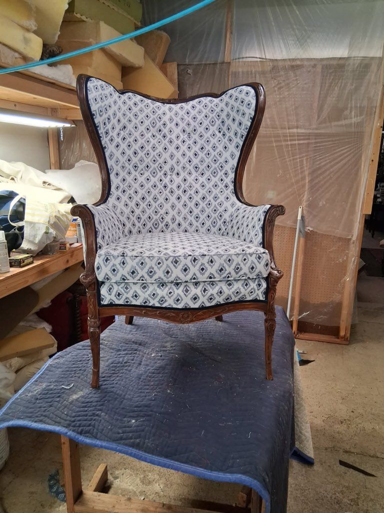 Antique upholstered armchair on a blue rug in a workshop or storage space