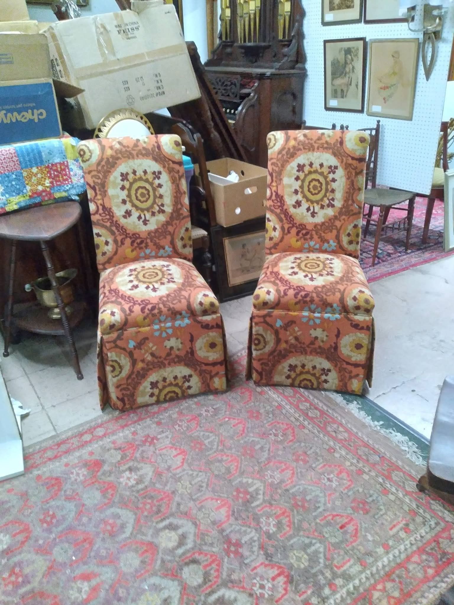 Two patterned chairs in a cluttered room with rugs and stacked boxes